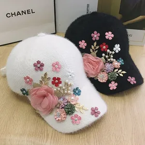 Detailed view of plush baseball caps with 3D floral accents and pearl bead decorations