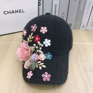 Detailed view of plush baseball cap featuring handmade floral accents and faux pearls