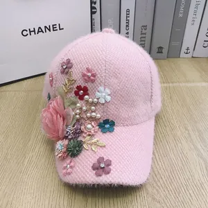 Detail of pink faux fur baseball cap featuring 3D floral embroidery and pearl accents