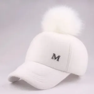 Detailansicht der weißen Plüsch-Baseballkappe mit Pelzbommel und M-Logo aus Metall