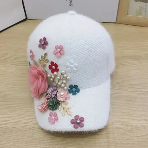 Detail of white plush baseball cap with floral silk petals and pearl embellishments