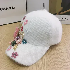 Detailed close-up of 3D floral accents and pearls on a white plush winter baseball cap