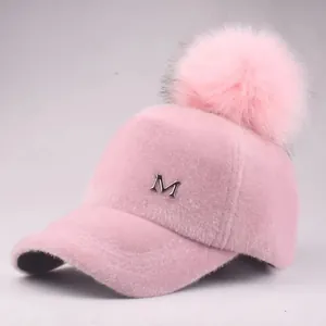 Detailansicht der rosa Plüsch-Baseballkappe mit Pelzbommel und silbernem M-Metall-Logo