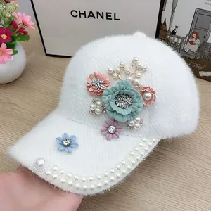 Detail of plush white baseball cap with floral fabric accents and pearl embellishments