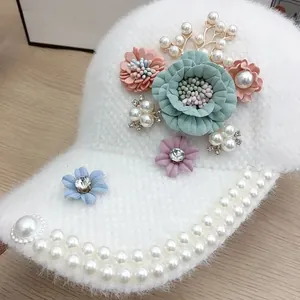 Close-up of white plush baseball cap featuring fabric flowers and pearl brim details