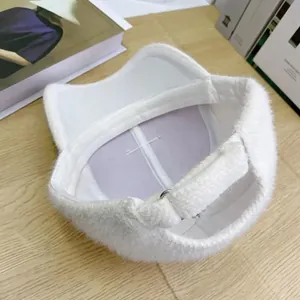 Détail d'une casquette en peluche blanche montrant la doublure mauve et la sangle réglable