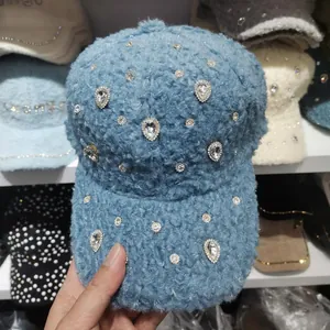Detailed close-up of blue fleece baseball cap with sparkling rhinestone heart accents
