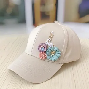 Close-up of beige baseball cap featuring 3D floral accents and golden deer embroidery