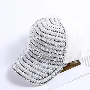 Detailed close-up of a white baseball cap with intricate pearl and rhinestone embroidery