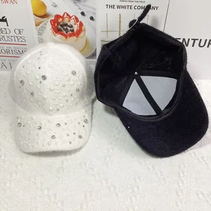 Winter faux fur baseball cap with pearls and rhinestones on a minimalist white desk