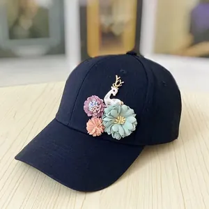 Detail of dark blue baseball cap featuring 3D fabric flowers and a white deer charm