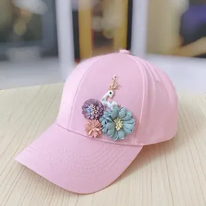 Close-up of pink baseball cap featuring 3D floral appliqués and gold-antler deer charm