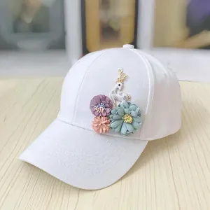 Detail of floral appliques and golden deer ornament on a white cotton baseball cap