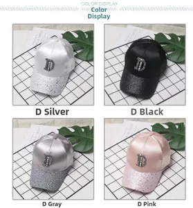Detail view of stylish women's satin baseball caps with rhinestone brims and D-letter tags