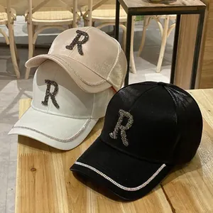 Three satin baseball caps with rhinestone letter R in gold, white and black colors
