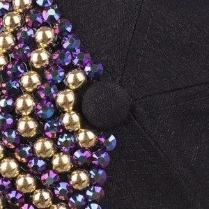 Detailed close-up of gold beads and purple rhinestones on a black cotton baseball cap
