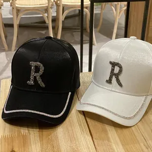 Stylish silk baseball caps in black and white with rhinestone R logo and brim trim