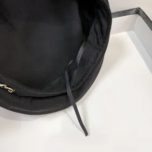 Details des verstellbaren Innenbands und der goldenen Kette an der schwarzen Baskenmütze