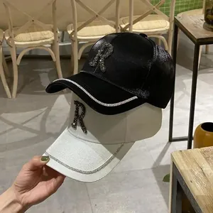 Detailed view of black and white satin baseball caps with rhinestone letter R and brim