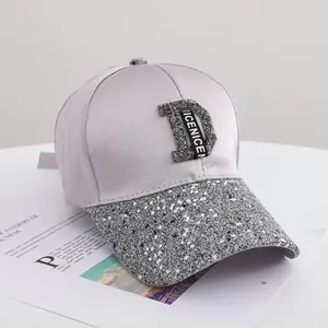 Detail of baseball cap with shimmering silver glitter D-logo and sleek satin texture