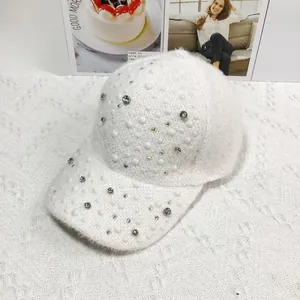 Close-up of white plush baseball cap with heavy rhinestone and pearl embellishments