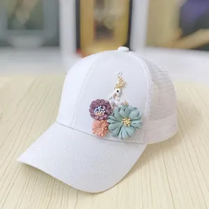Close-up of white mesh baseball cap featuring handmade 3D cloth flowers and golden deer charm