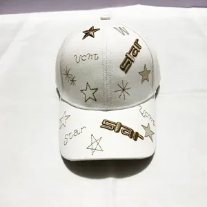 Détail de la broderie étoile dorée sur une casquette en coton blanc texturé