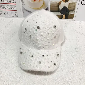 Close-up of white plush baseball cap with sparkling rhinestones and pearl embellishments