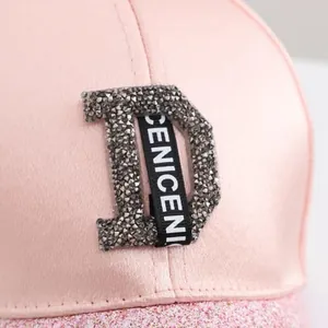 Detail of light pink satin baseball cap with rhinestone D logo and shimmering sequins