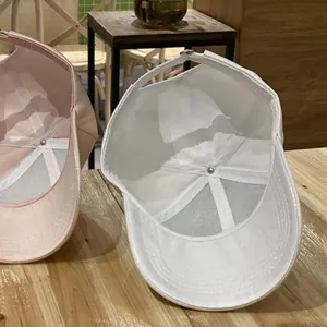 Detail view of pink and white baseball caps showing interior mesh and adjustable buckle