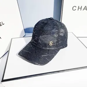Detailed view of black tweed baseball cap with silver stitching and gold metal logo