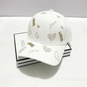 Dettaglio del cappellino bianco in cotone con ricami di cuori dorati e scritta LOVE