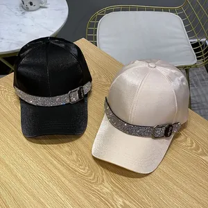 Luxe satin baseball caps in black and pink with rhinestone trim on a wooden surface
