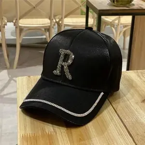 Detail of black rhinestone baseball cap with silver R letter on rustic wood table