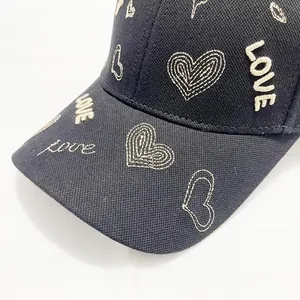 Dettaglio del ricamo a cuore e della scritta LOVE sul berretto da baseball nero