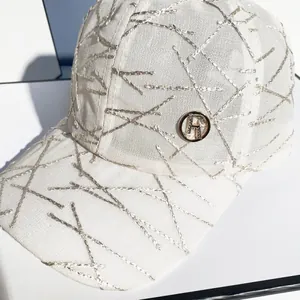 Close-up of white baseball cap with silver embroidery and rhinestone R logo detail