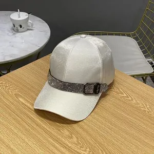 Detail of white satin baseball cap with rhinestone headband and black metal buckle