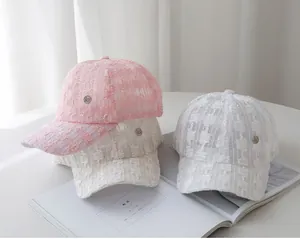 Detail of lace texture and M logo on stylish pink, beige and white baseball caps