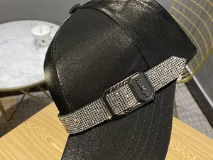 Close-up of rhinestone side band and engraved metal plate on black satin baseball cap
