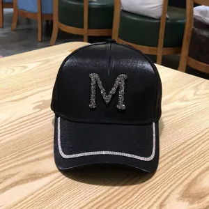 Detailed view of black mercerized baseball cap featuring a sparkling rhinestone M letter