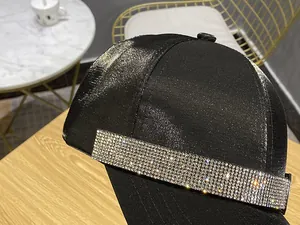 Close-up of sparkling rhinestone headband detail on a premium black satin baseball cap