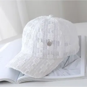 Close-up of white lace baseball cap featuring breathable hollow texture and metal badge detail