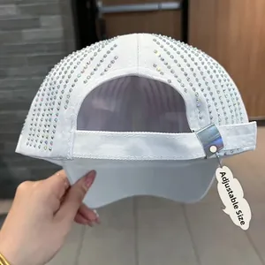 Detail of adjustable metal buckle and rhinestone embellishment on white baseball cap