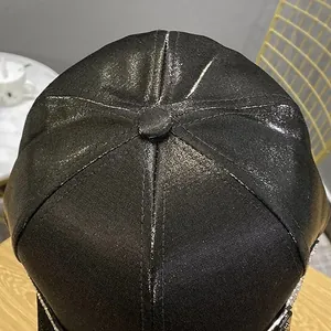 Detail of a black shimmering baseball cap with rhinestone trim on the visor edge