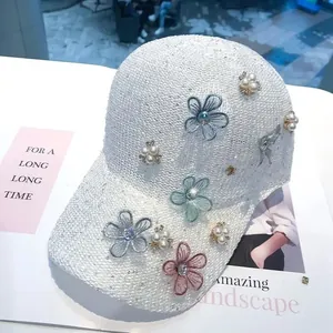 Detailed shot of white sequin baseball cap featuring lace flowers and pearl buttons