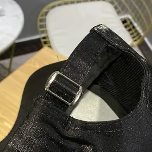 Close-up of black glitter baseball cap showing adjustable silver buckle and fabric texture
