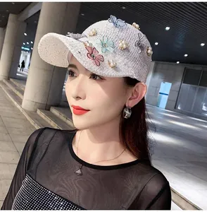 Close-up of a white knitted baseball cap featuring 3D floral embroidery and pearls