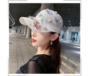 Detail of white hollow-out knit fabric with floral embroidery and pearl accents on hat