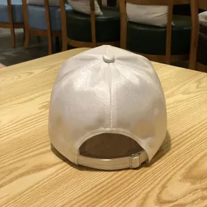 Detail view of white satin baseball cap back with adjustable metal buckle and stitching