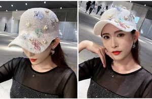 Detail of white knit mesh baseball cap featuring colorful fabric flowers and pearl accents